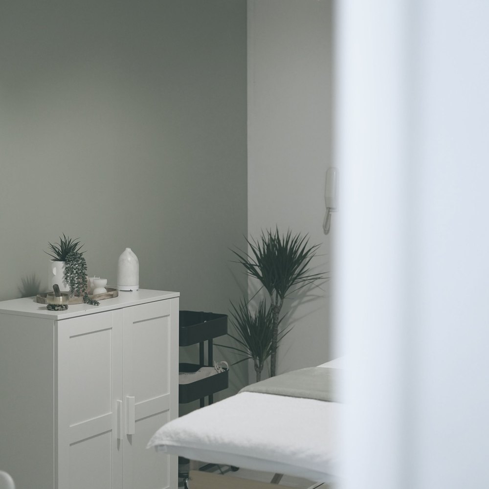 A quiet treatment room, bed made, light from one side